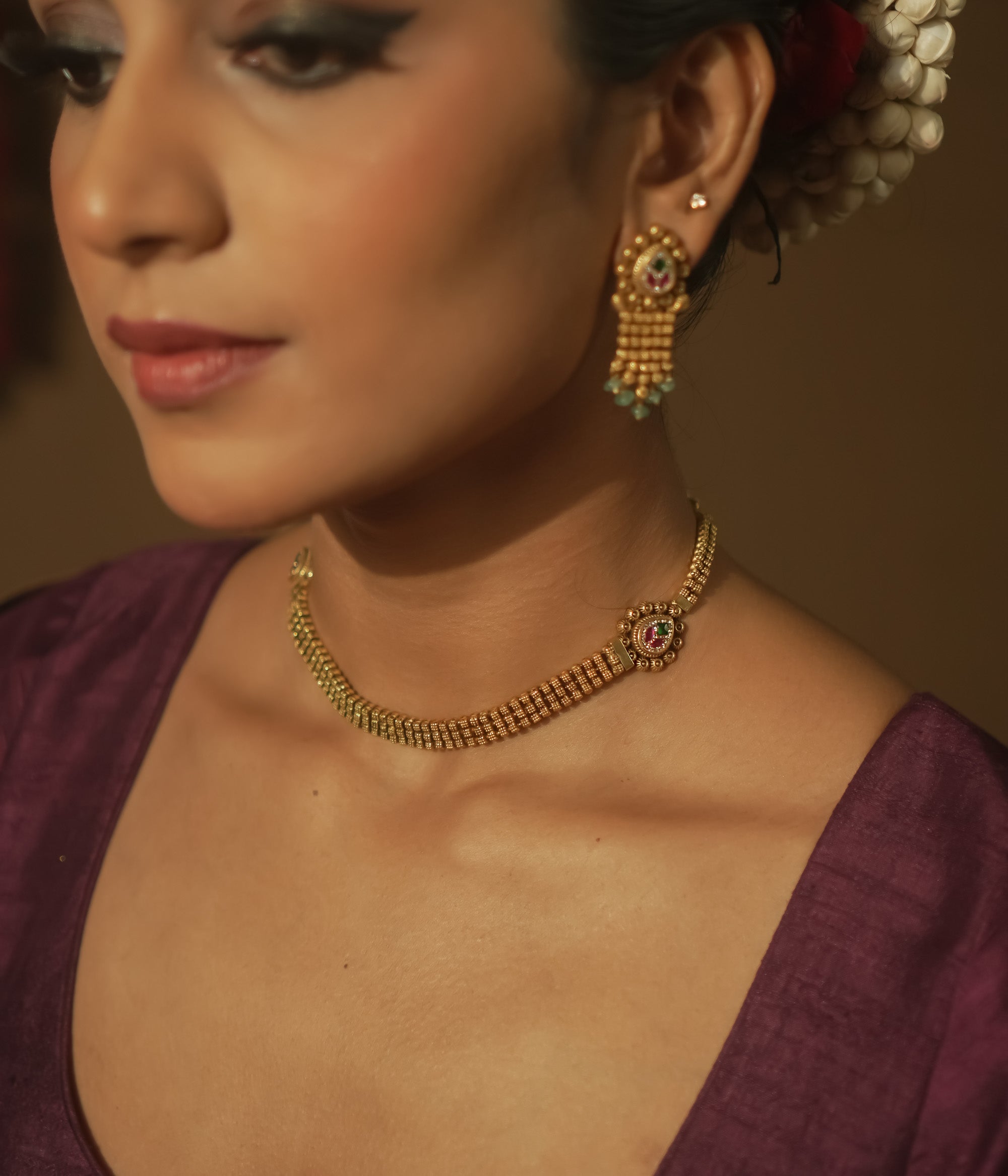 Gold mesh necklace with a gemstone pendant surrounded by tiny gold dots.