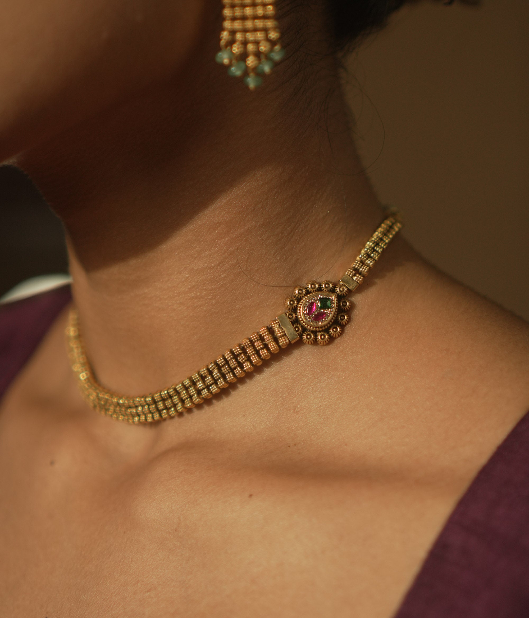 Gold mesh necklace with a gemstone pendant surrounded by tiny gold dots.