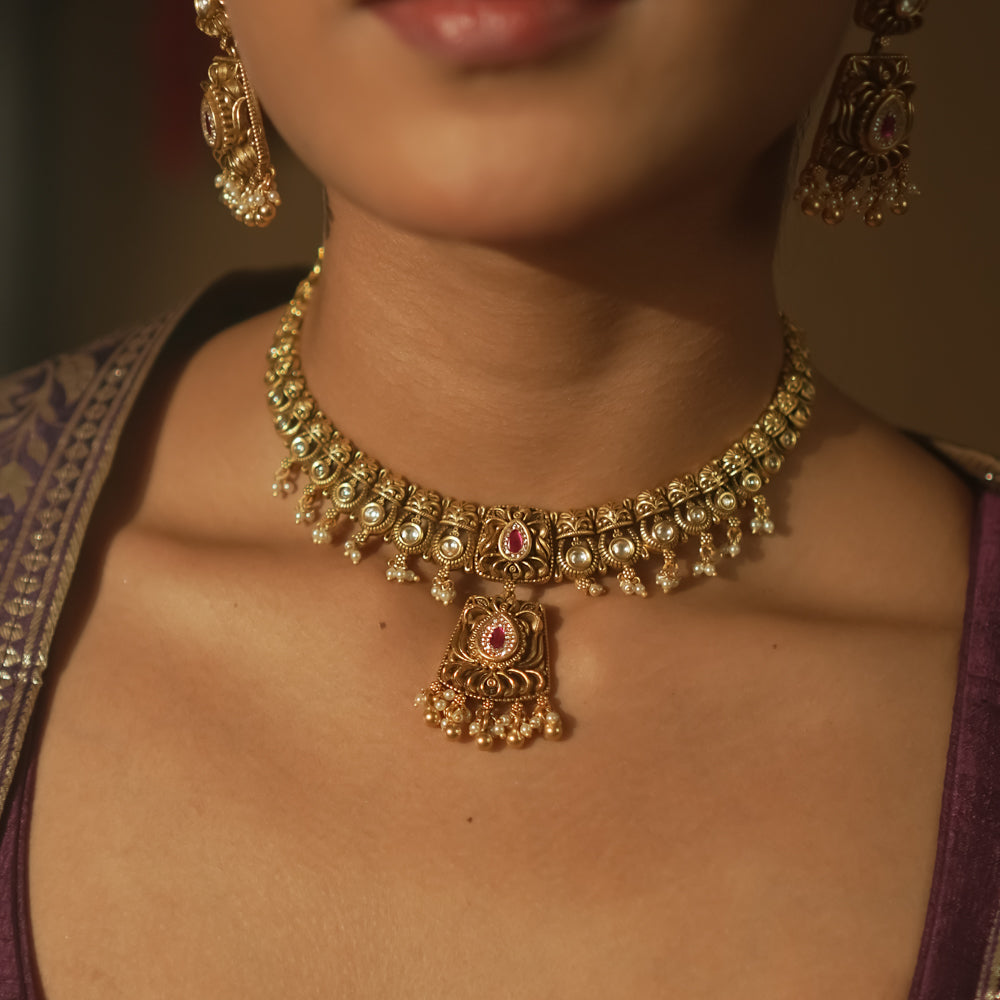 Gold mesh necklace with a central pendant with pearls and crimson gems.