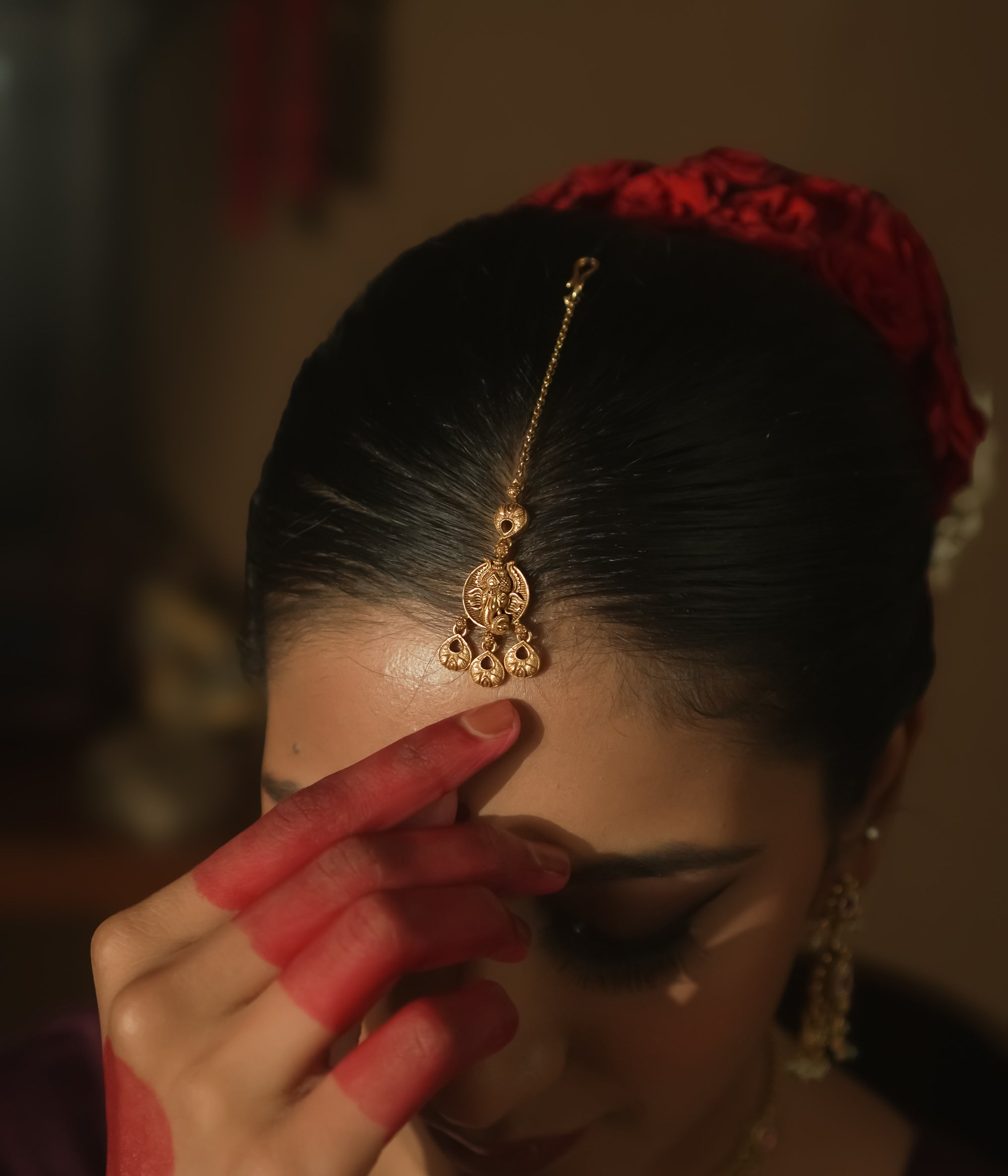 Gold maangtika with a delicate chain and ornate dangling teardrops.