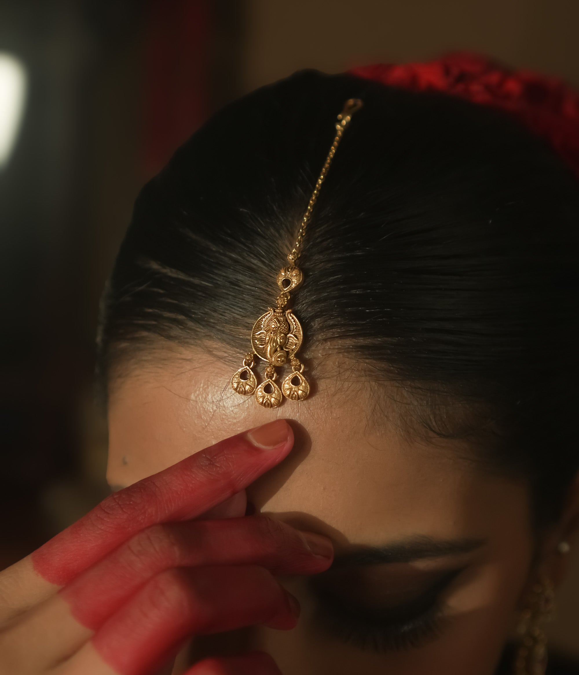 Gold maangtika with a delicate chain and ornate dangling teardrops.