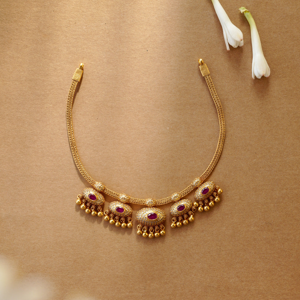 Traditional gold necklace with red spinal stones and dome motifs from Navratna Collection.