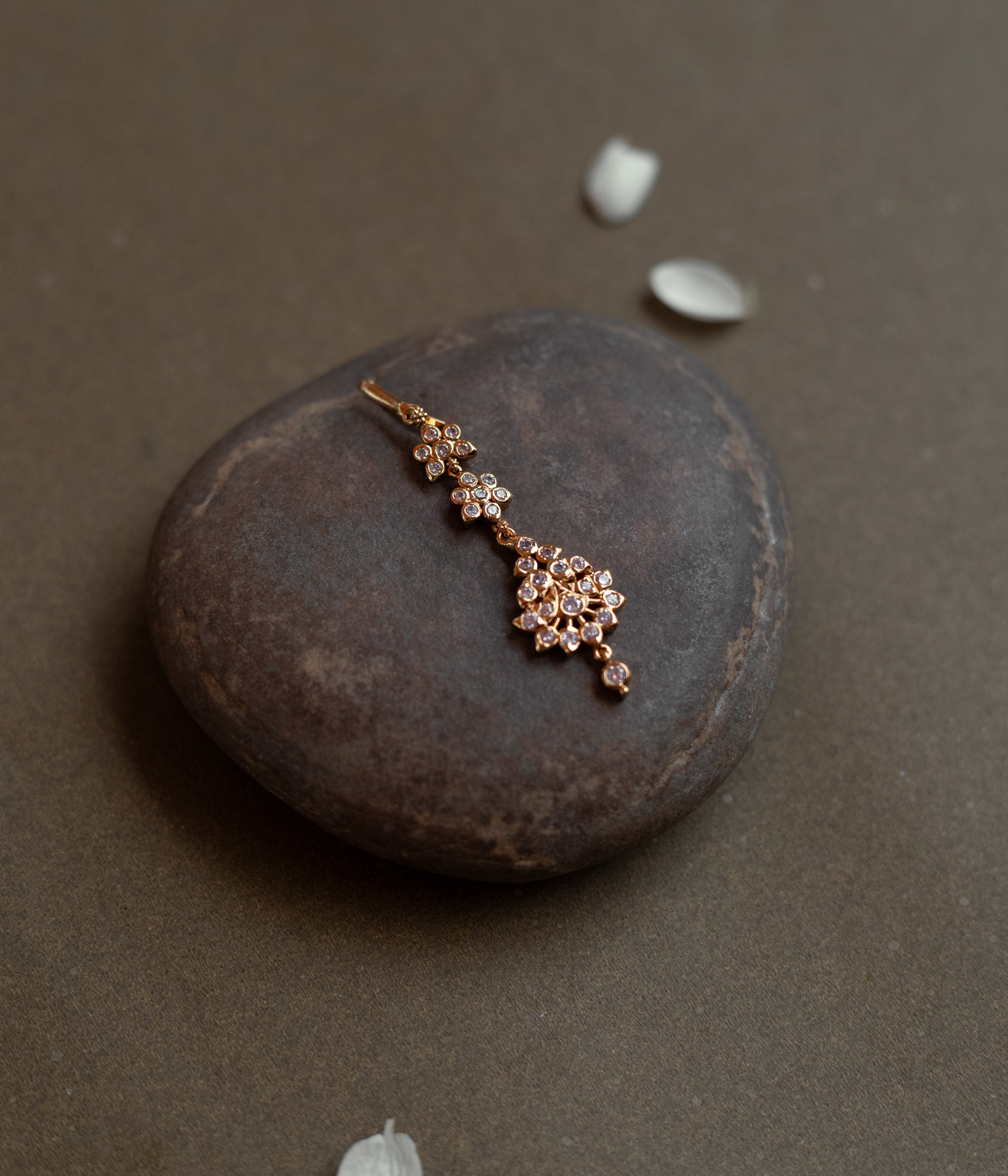 Elegant tikka with floral-shaped Swarovski stone design placed on a natural stone background.