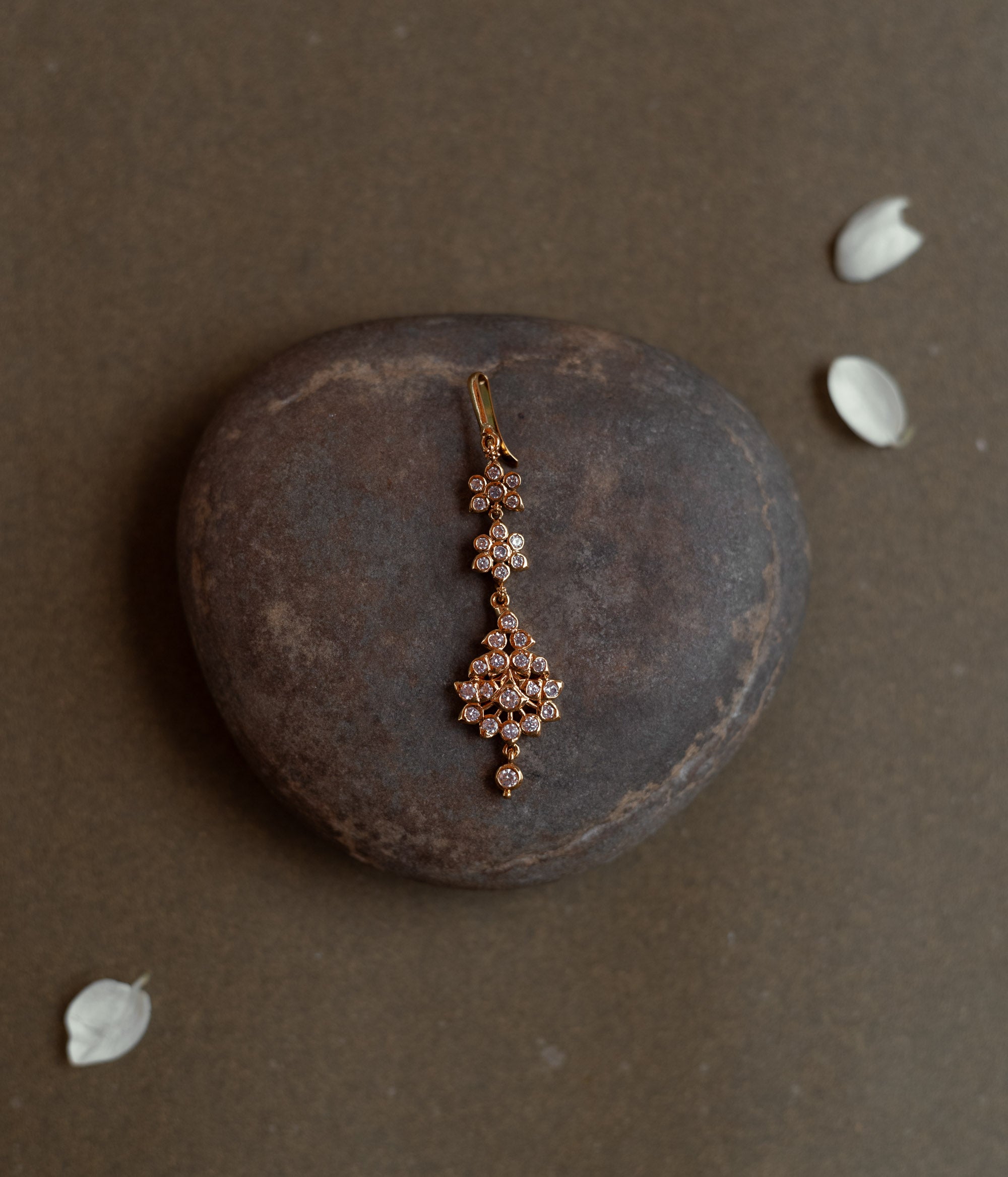 Elegant tikka with floral-shaped Swarovski stone design placed on a natural stone background.