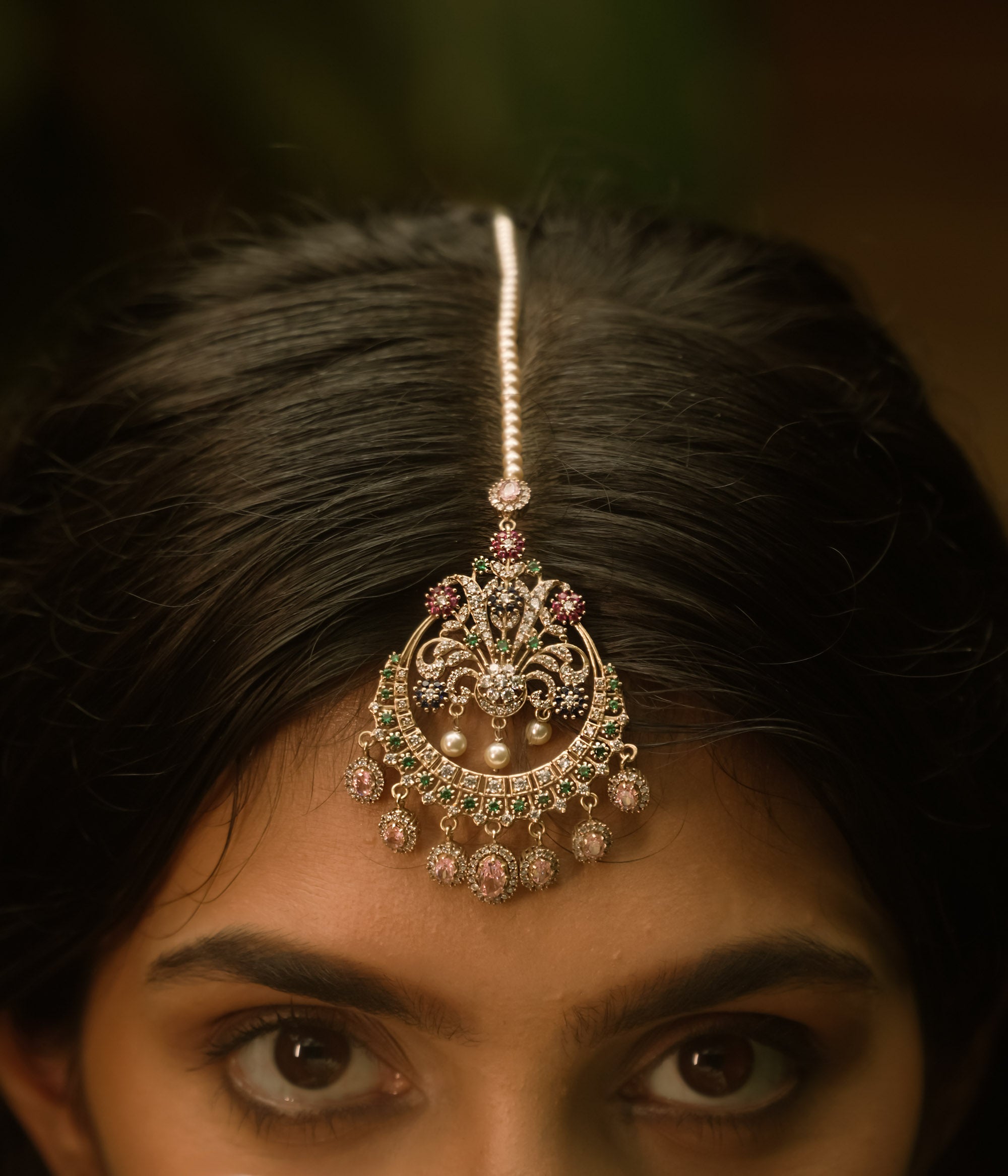 Traditional tikka with Swarovski stones, pink Kundan, and pearl drops in a floral crescent design.