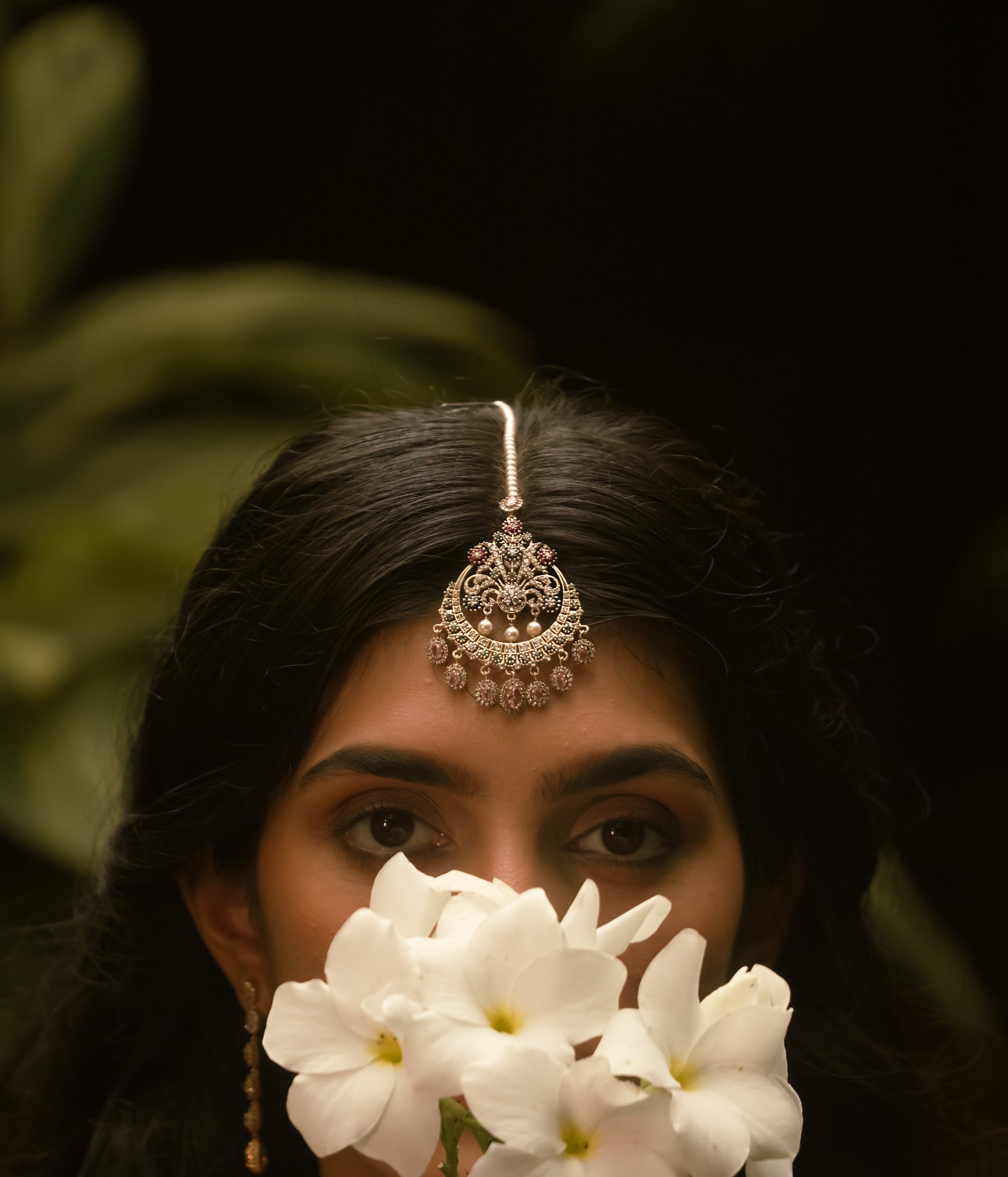 Traditional tikka with Swarovski stones, pink Kundan, and pearl drops in a floral crescent design.