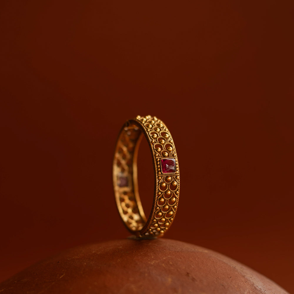 Tribal bangle with red spinal stones and feather-inspired design motifs.