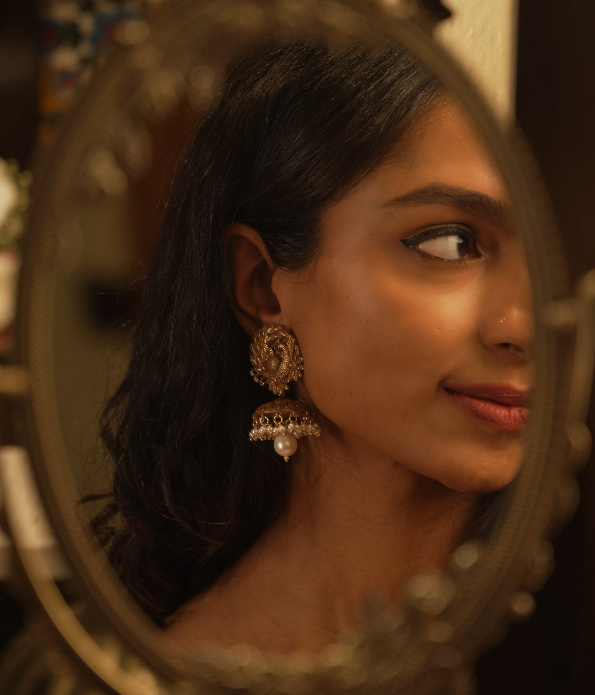 Tribal-style jhumka earrings with spiral top design, red spinel accents, and hanging pearl drop.