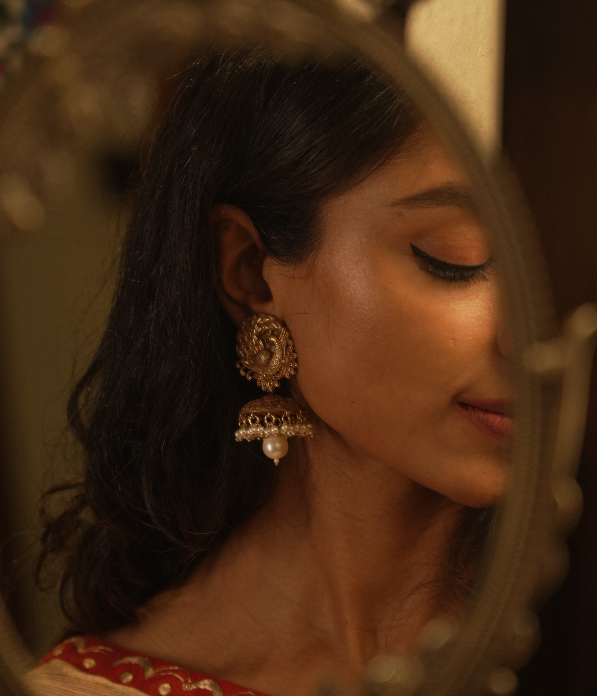 Tribal-style jhumka earrings with spiral top design, red spinel accents, and hanging pearl drop.