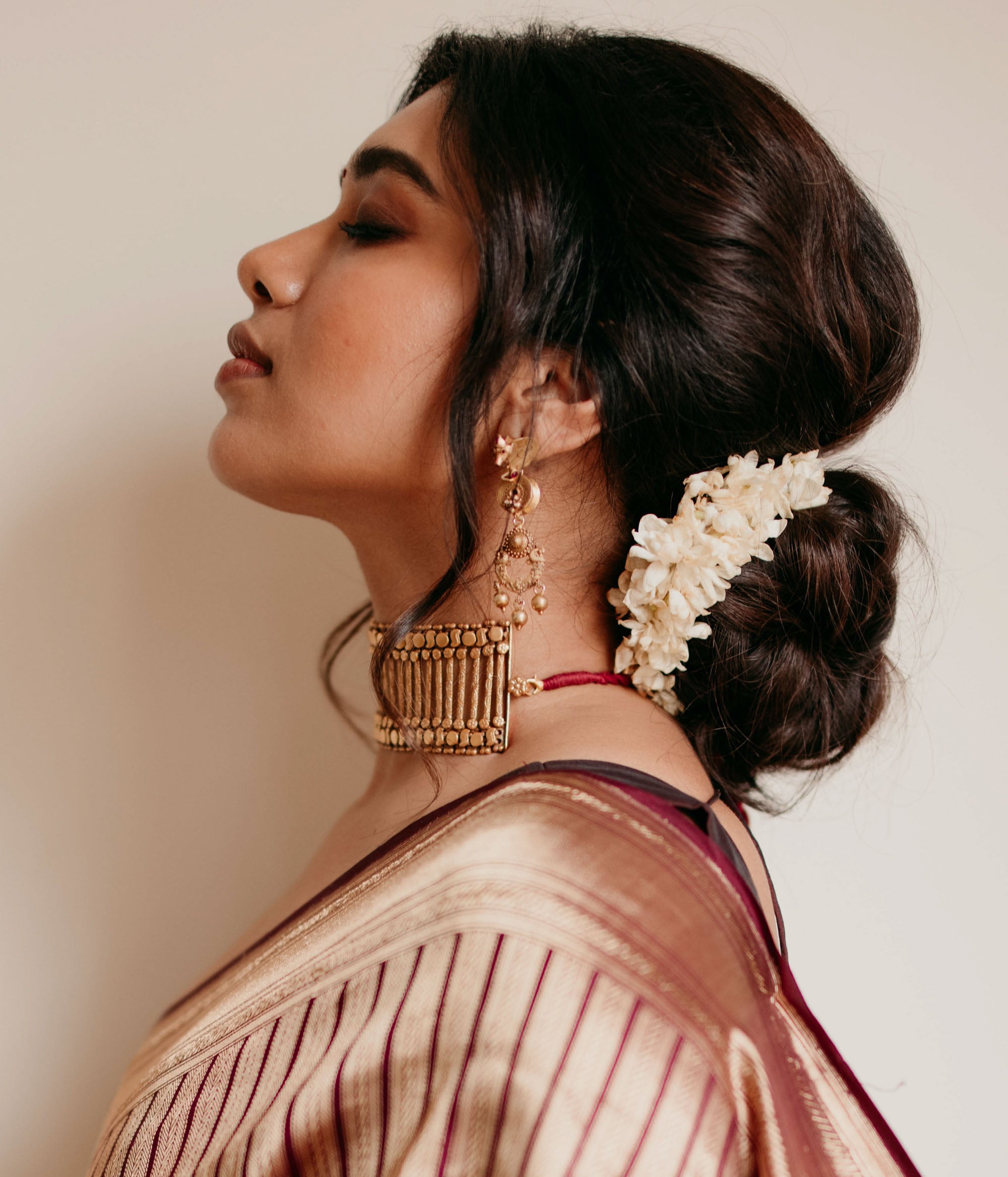 Gold tribal earrings with dangling design and Red Spinal Stones, styled with traditional jasmine hairdo.
