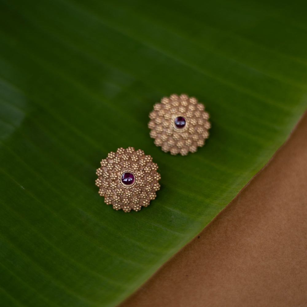 Thara earrings featuring red spinel stones in a floral crest design, made of 92.5 sterling silver with 22ct gold plating.