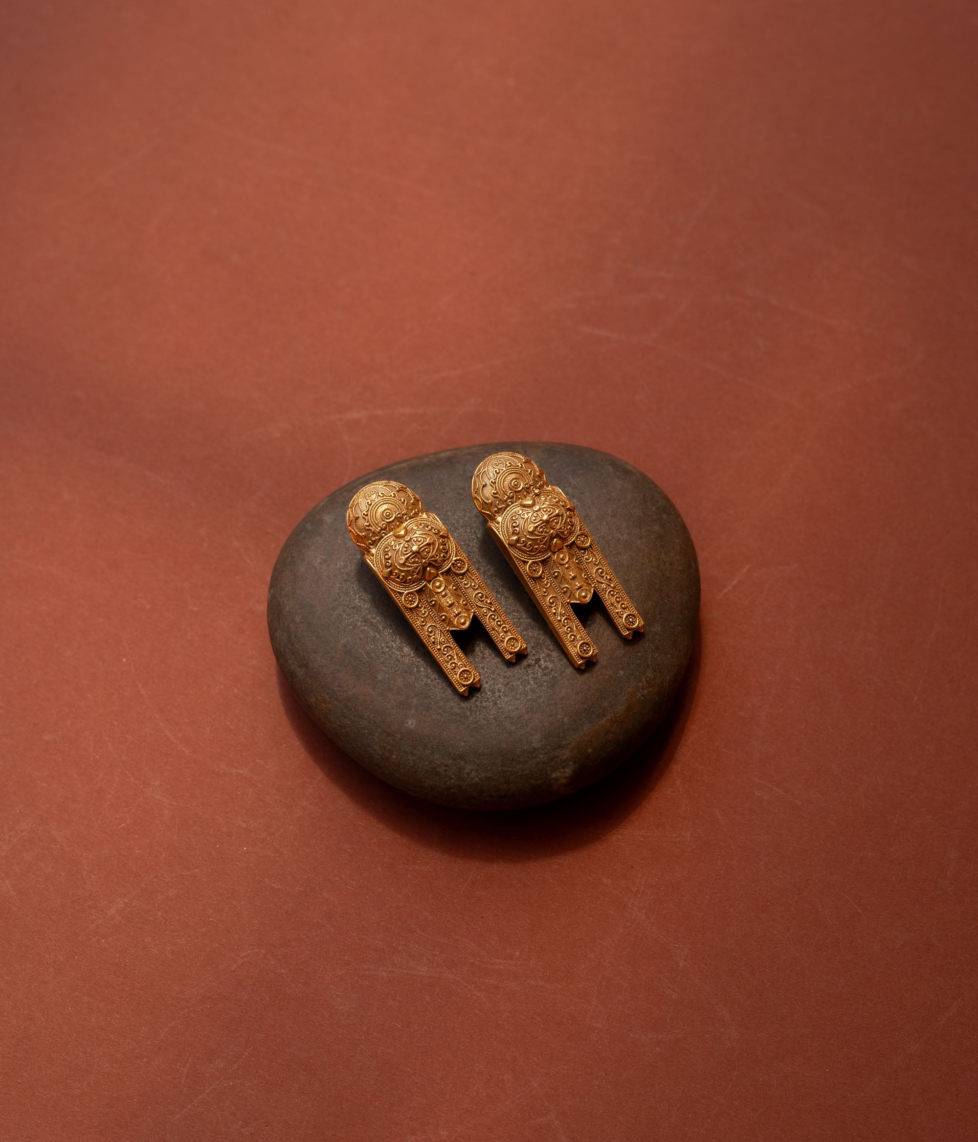 Gold tribal earrings with lion motif and yantra-inspired patterns from the Tribal Collection.
