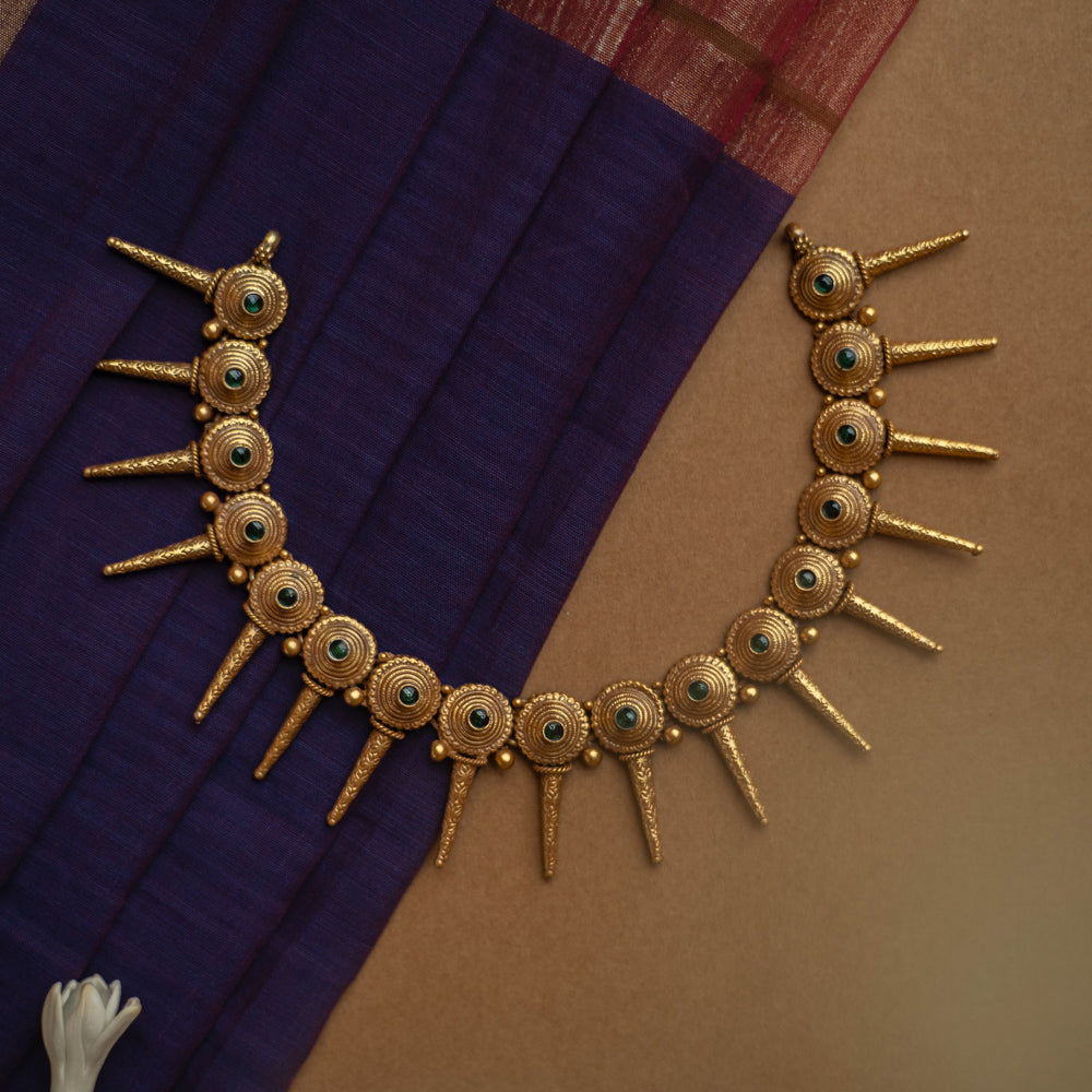 Antique gold necklace with radiating spike motifs, each set with a green spinel stone.