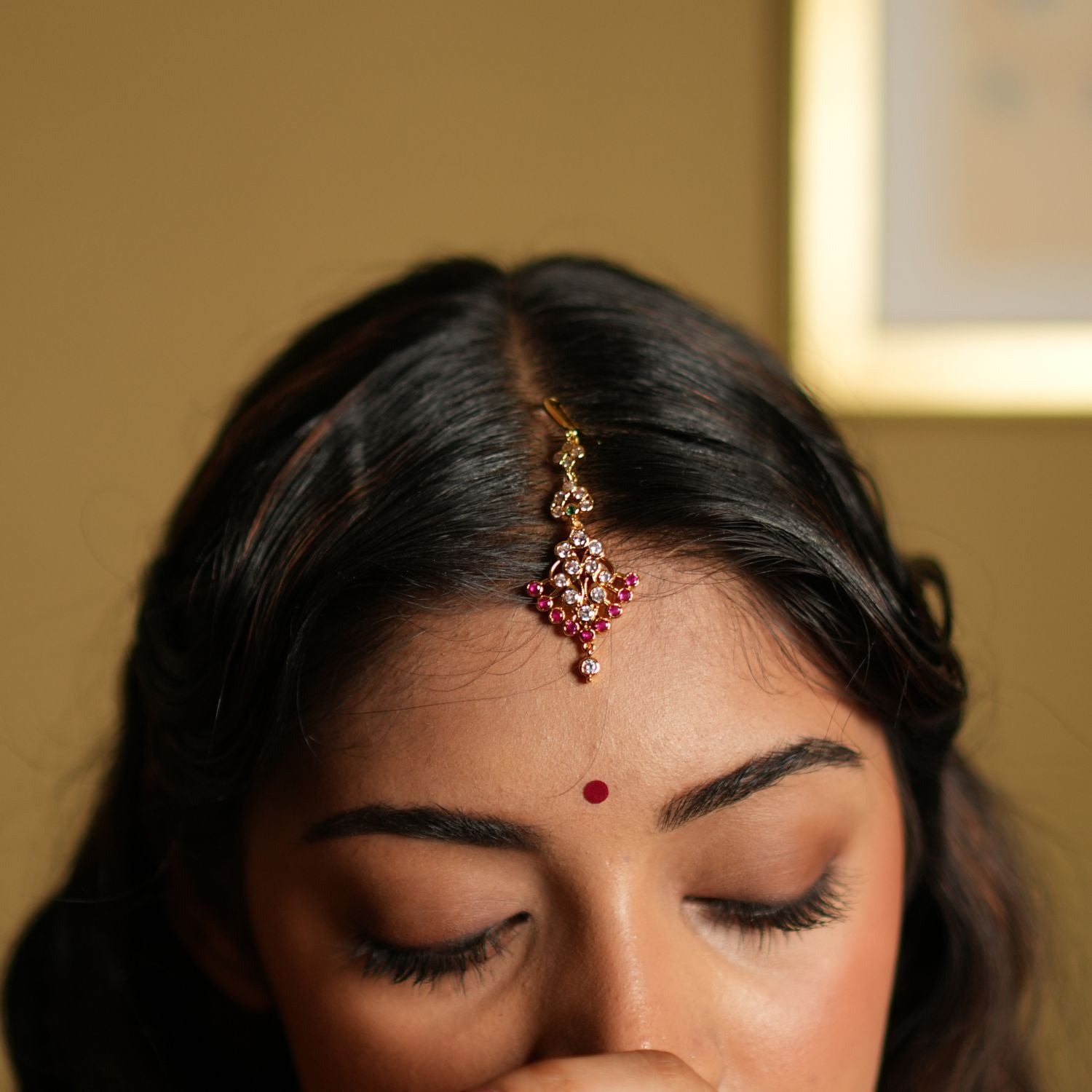  Maang Tikka, meticulously crafted from 92.5 sterling silver and finished with a rich 22-carat gold plating. The intricate design showcases a beautiful arrangement of vivid pink gemstones and sparkling white stones, creating a perfect balance of elegance and vibrancy. Ideal for weddings, festivals, and special occasions, this Maang Tikka gracefully enhances your forehead, adding a timeless charm to your look.