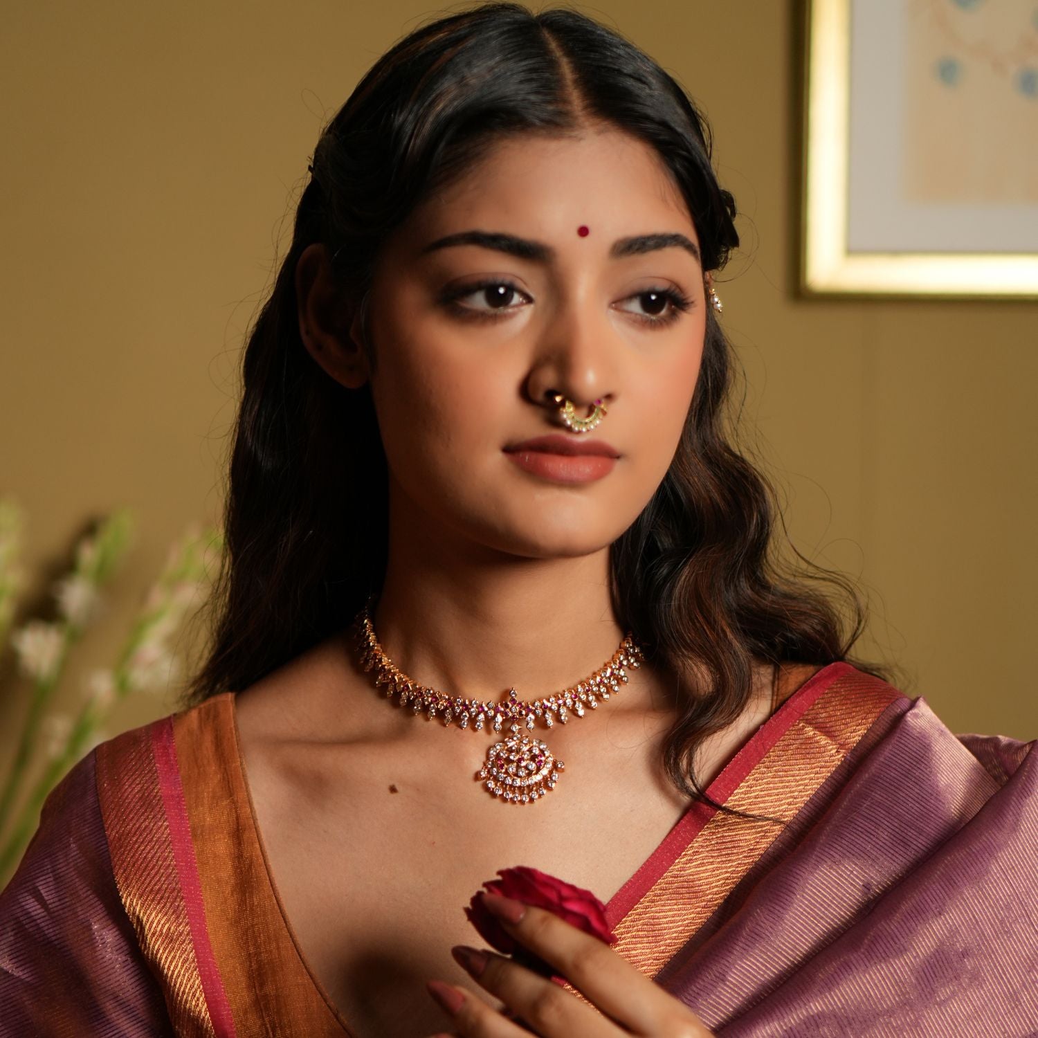 Elevate your traditional attire with this exquisite Attigai necklace, crafted from 92.5 sterling silver and finished with a rich 22-carat gold plating. Adorned with dazzling Swarovski crystals and accented with vivid pink gemstones, this necklace exudes timeless elegance and sophistication. 