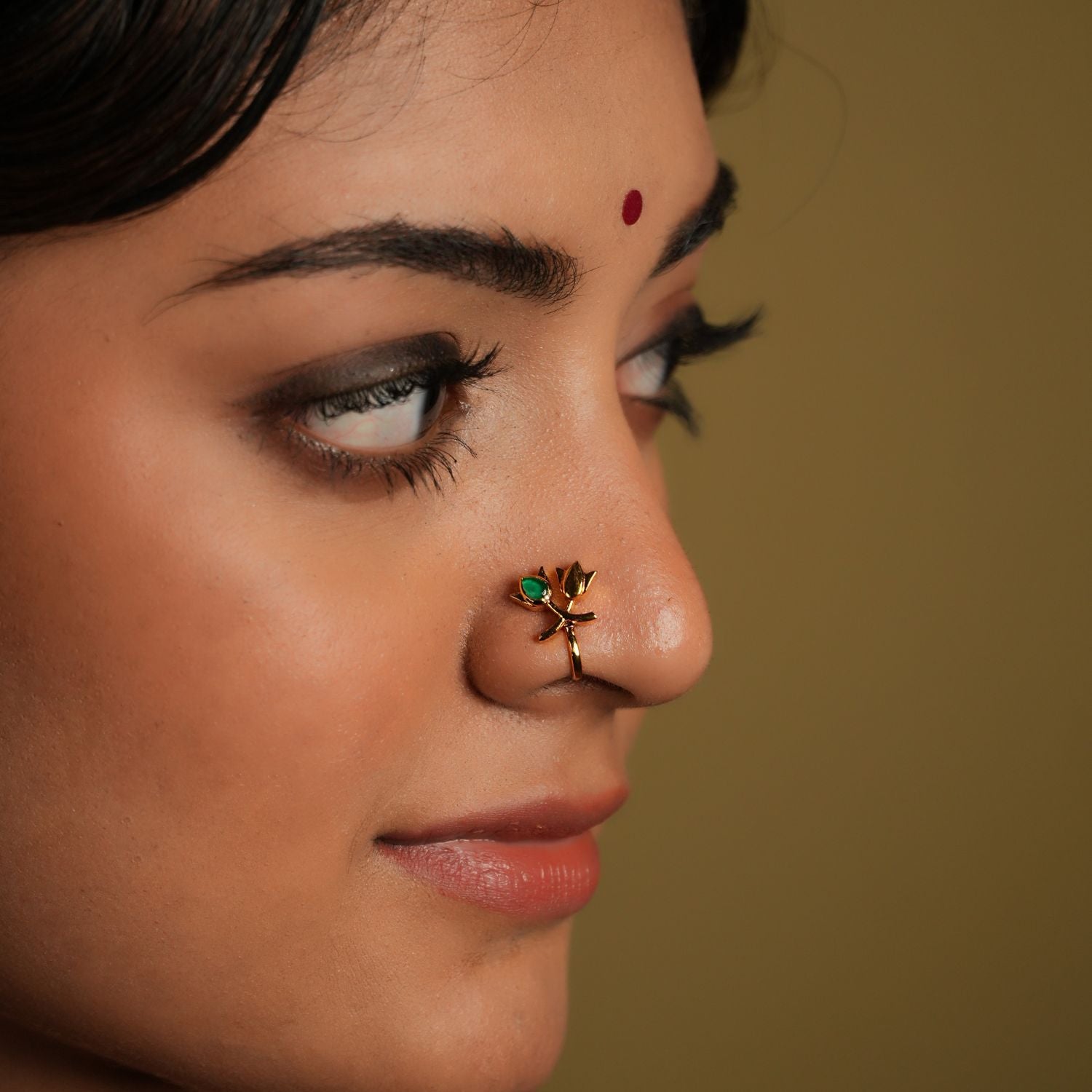 This beautiful nose pin is a blend of traditional artistry and modern design, crafted from 925 sterling silver, ensuring both durability and elegance. It features a stunning kundan stone at its center, which is known for its intricate setting and radiant shine. The lotus-shaped design adds a touch of grace, symbolizing purity and beauty.