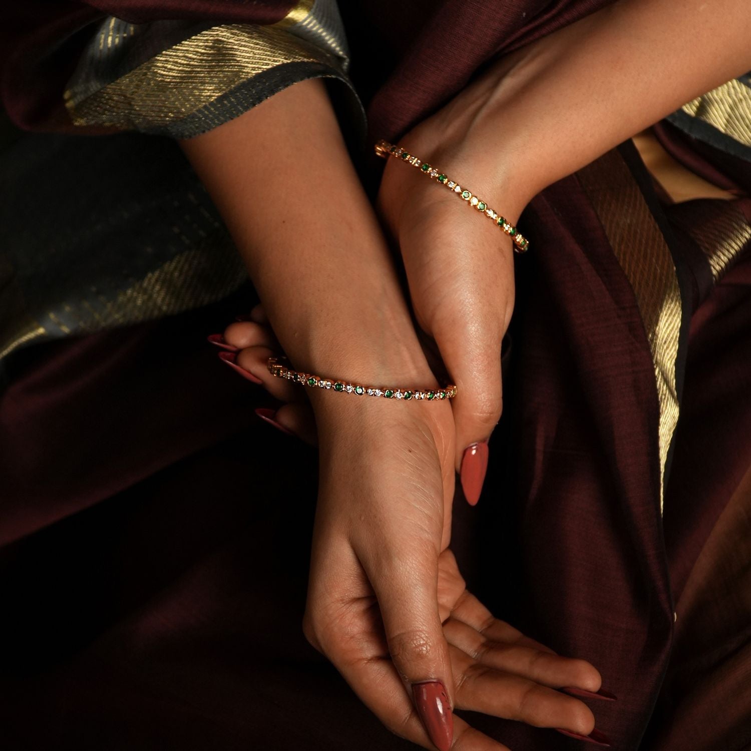 This exquisite bangle is crafted from high-quality 925 sterling silver and beautifully gold-plated for a luxurious finish. The design features delicate circular motifs, each set with shimmering stones that enhance its subtle elegance. Accented with green gemstones, it draws inspiration from the lush landscapes of Tamil Nadu, offering a whimsical touch to its refined aesthetic.