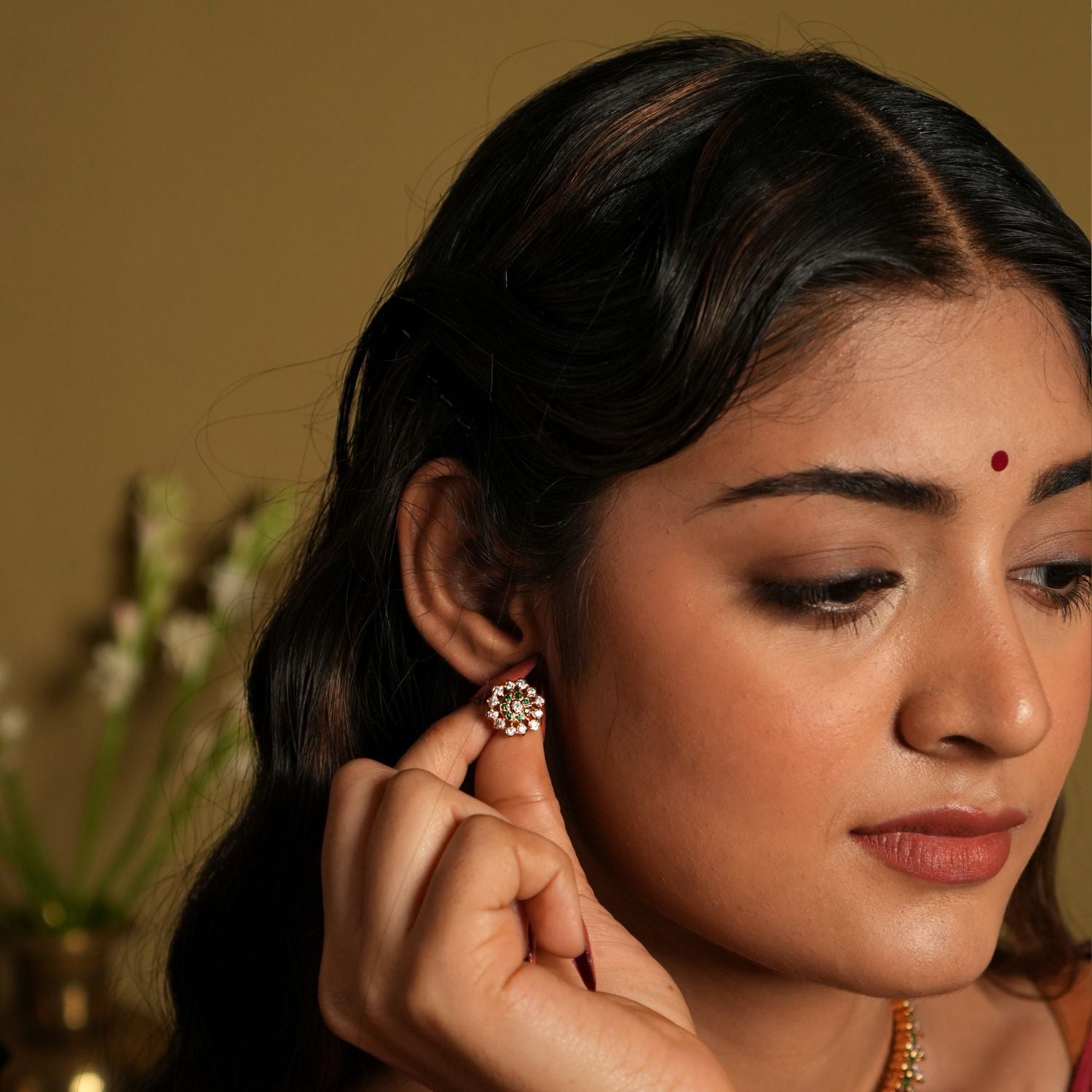 This image showcases a pair of elegant stud earrings crafted from 92.5 sterling silver and adorned with Swarovski stones. The earrings feature a gold-plated finish, adding a touch of sophistication and luxury to their design.