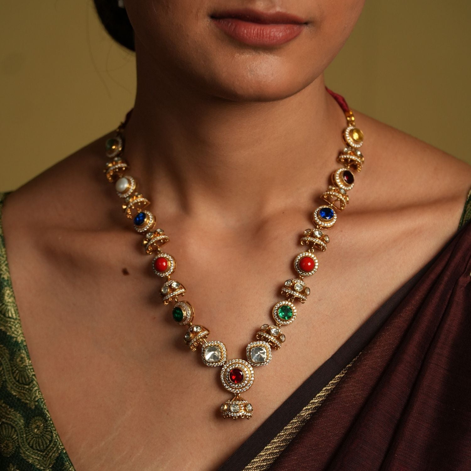 Embrace traditional elegance with this exquisite necklace, inspired by the timeless beauty of Navratan jewelry. This stunning piece features a central pendant design, likely crafted from silver with moissanite polkis and navrtana stones, gold  plated