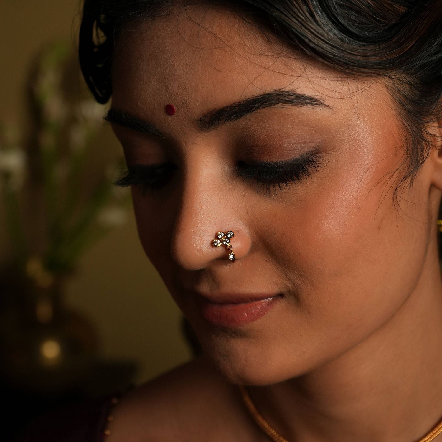 92.5 silver gold plated. This minimal nose stud shines with understated elegance,
featuring a moissanite set stone. A dangling moissanite drop adds a touch of delicate charm,
inspired by vintage Chettinad design language. A tiny, timeless treasure that exudes refined
sophistication.