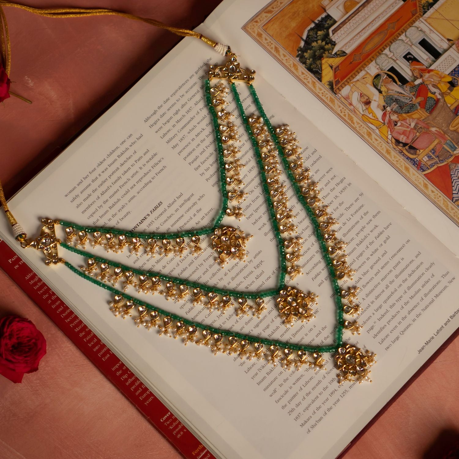 Elegant gold-plated silver necklace featuring layers of vibrant green beads intertwined with intricate white sapphires and pearl embellishments. The necklace showcases three floral-shaped pendants adorned with shimmering white sapphire stones, exuding a regal and traditional charm.