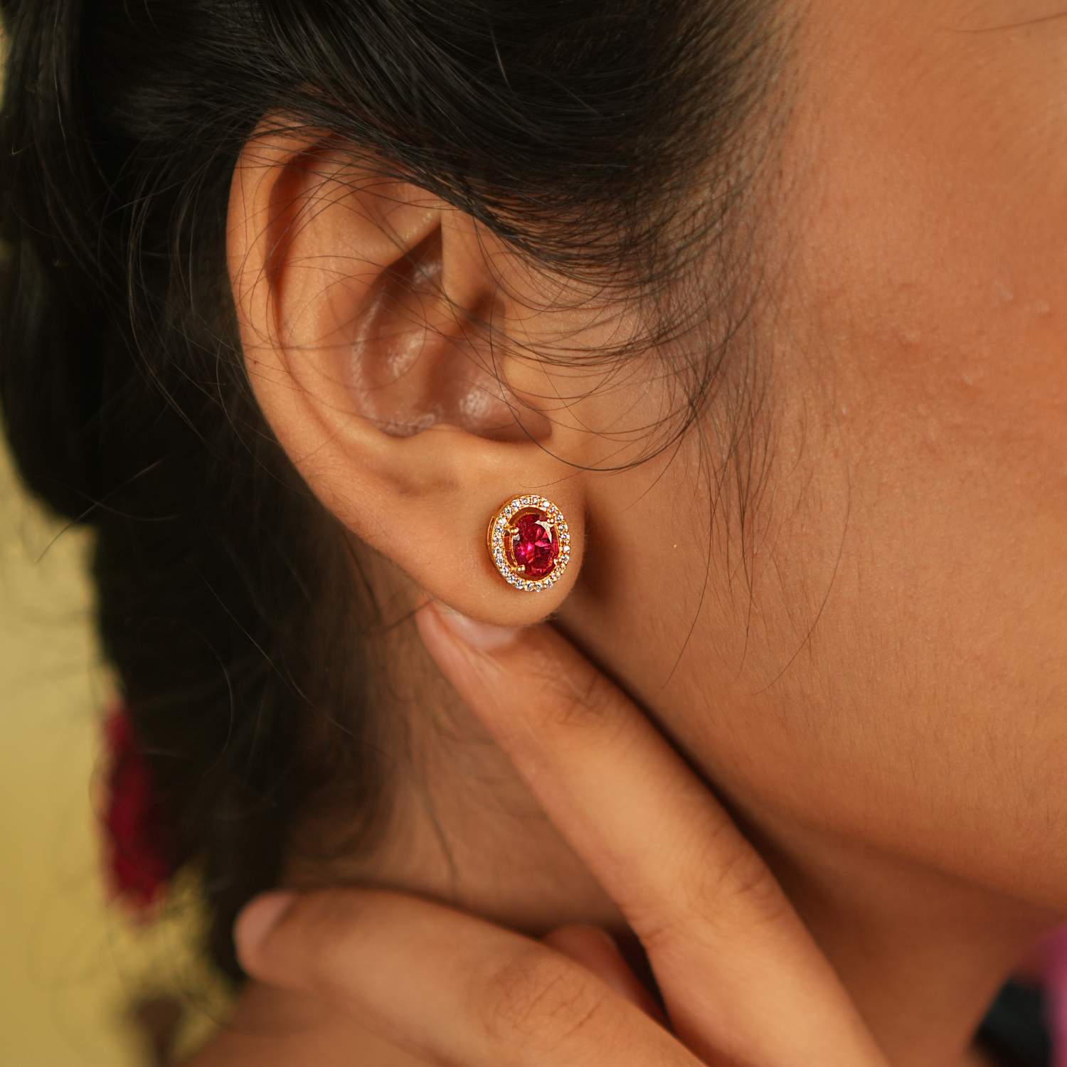 A delicate stud earring adorned with a captivating pink cut stone, encircled by shimmering Moissanite, exudes timeless charm and brilliance.