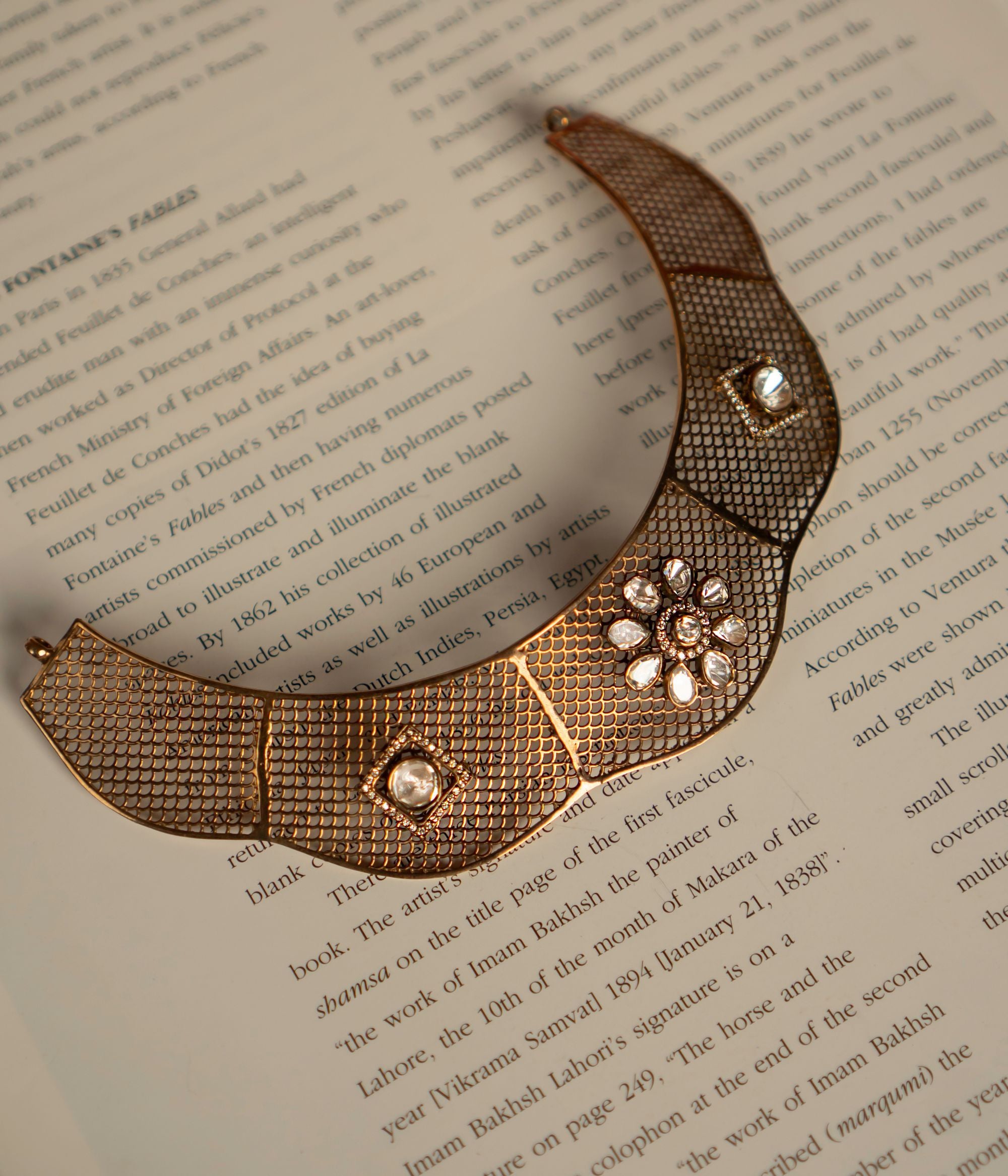 An exquisite gold-plated silver choker showcasing an intricate mesh design, adorned with dazzling CZ stones and Polki stones. The structured silhouette highlights a floral-shaped Polki motif, elegantly framed by fine CZ stone detailing, adding a regal touch. The seamless fusion of textures and embellishments exudes a luxurious, vintage charm, making this choker a timeless statement piece.