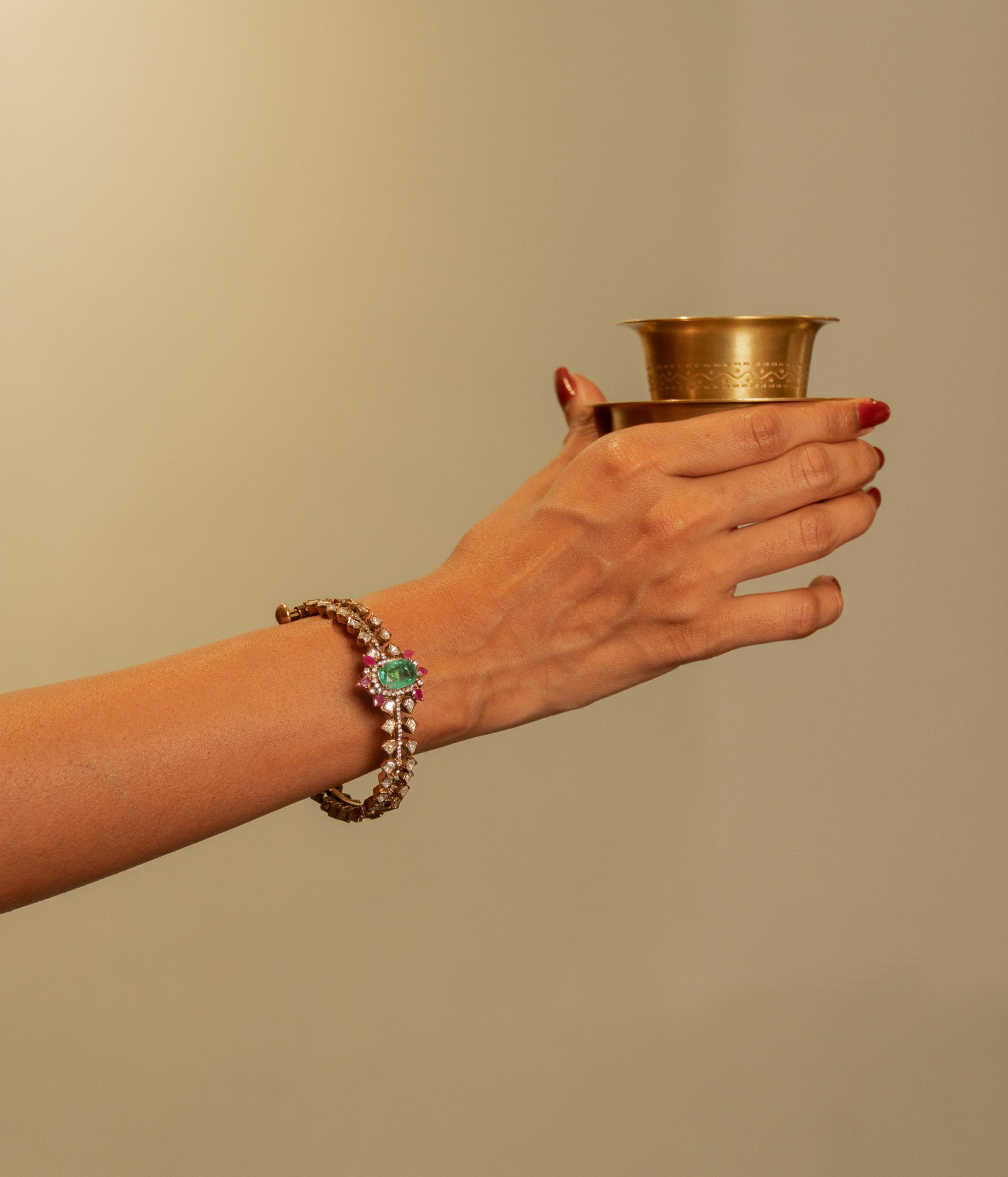 Gold Victorian bangle with a central green gemstone, surrounding polki and CZ stones, worn on a woman's wrist.