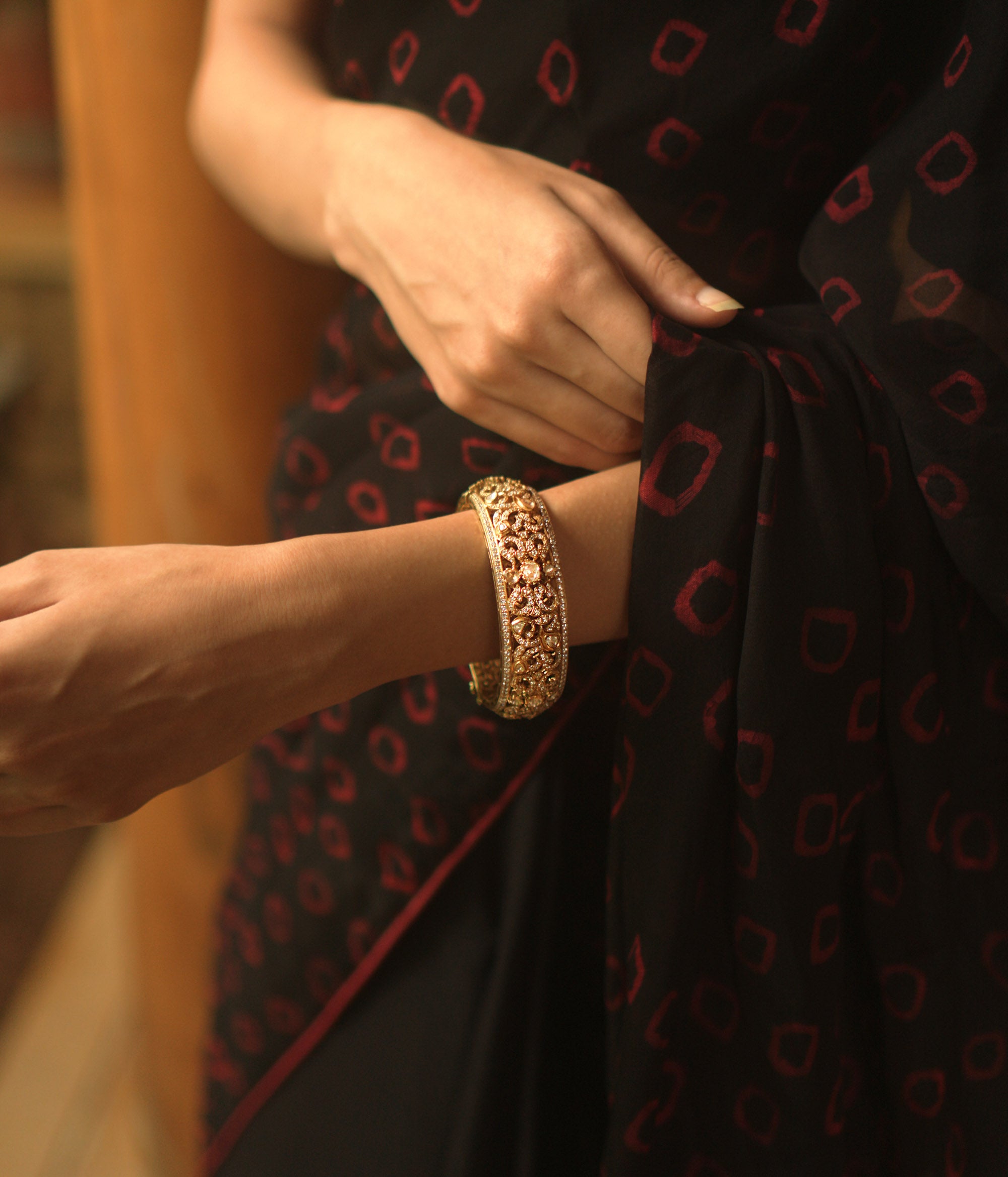 A gold bangle with intricate filigree and royal carvings.
