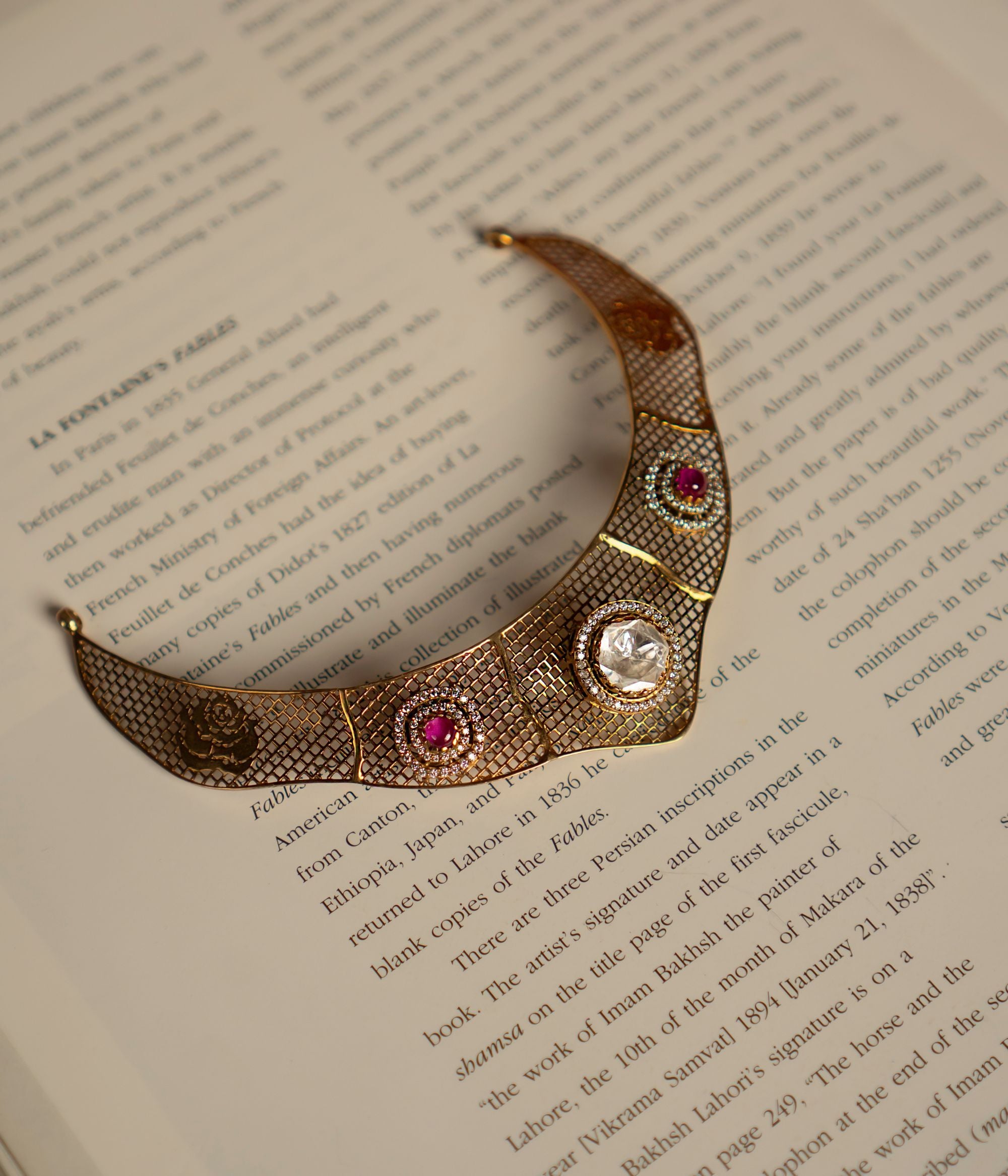 Elegant gold-plated silver choker featuring an intricate mesh design adorned with dazzling CZ stones, Polki stones, and vibrant red cut stones. The structured silhouette showcases a central Polki stone surrounded by fine detailing, complemented by red cut stones on either side, adding a regal touch. The fusion of textures and embellishments exudes a luxurious, vintage charm, making it a perfect statement piece.