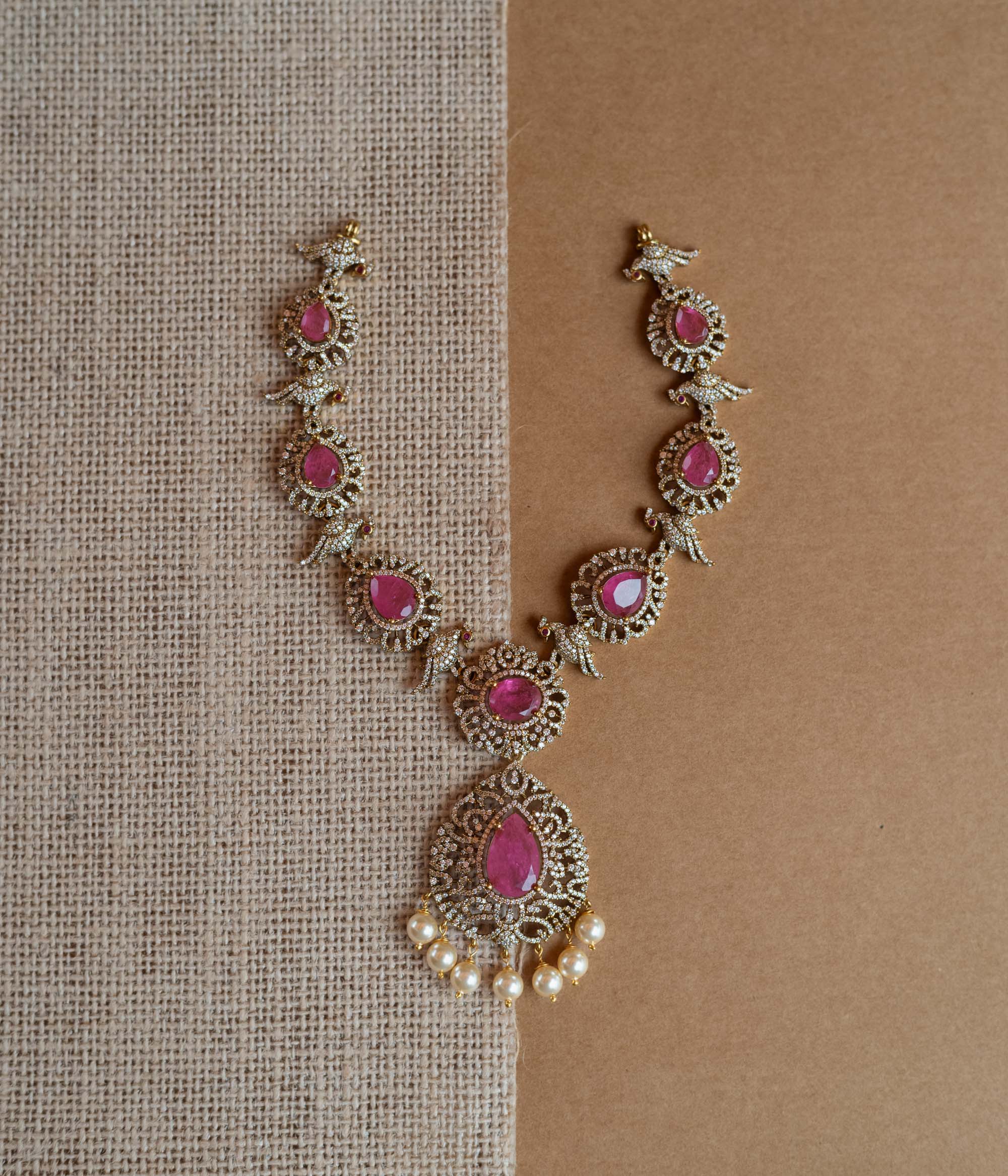 Gold Victorian necklace with pink gemstones, CZ stones, bird motifs, and dangling pearls.