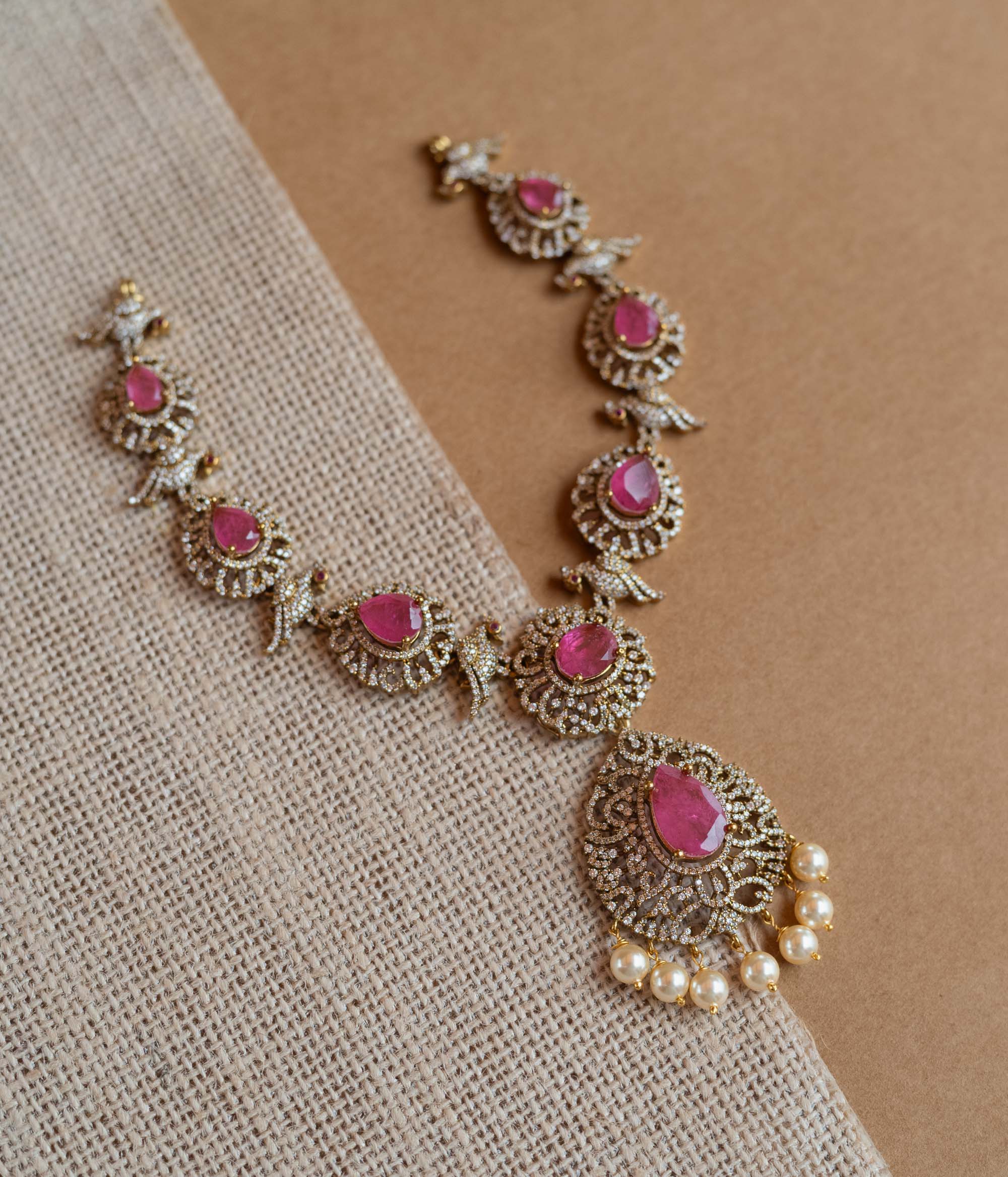 Gold Victorian necklace with pink gemstones, CZ stones, bird motifs, and dangling pearls.