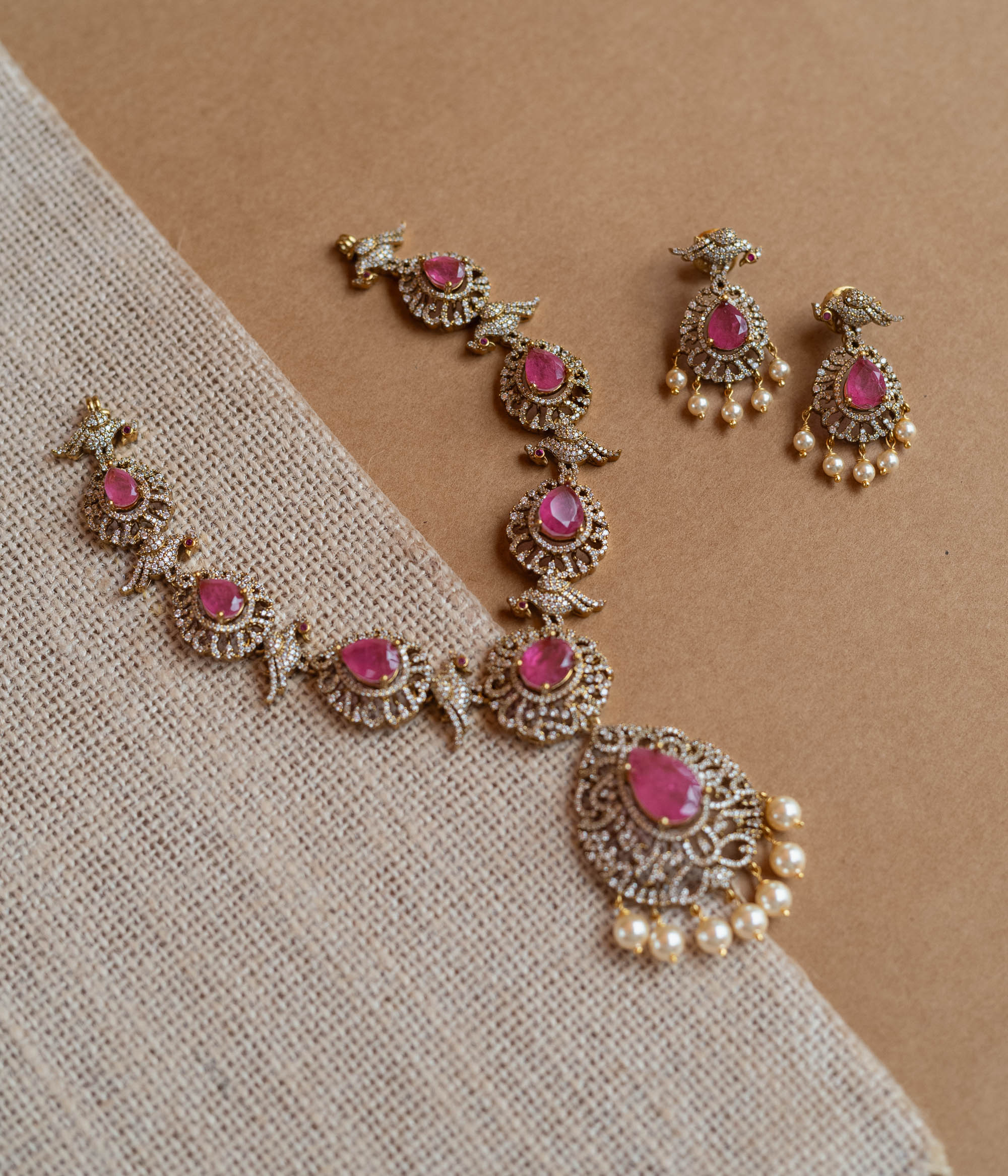 Gold Victorian necklace with pink gemstones, CZ stones, bird motifs, and dangling pearls.
