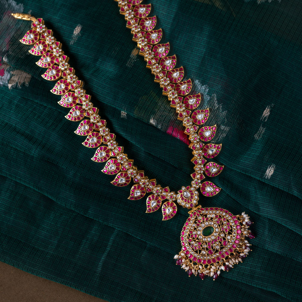 A handcrafted two-sided Kundan necklace in 92.5 sterling silver with 22ct gold plating, adorned with red, white, and green Kundan stones, red beads, and pearls. This versatile masterpiece exudes timeless elegance, blending heritage craftsmanship with regal charm.
