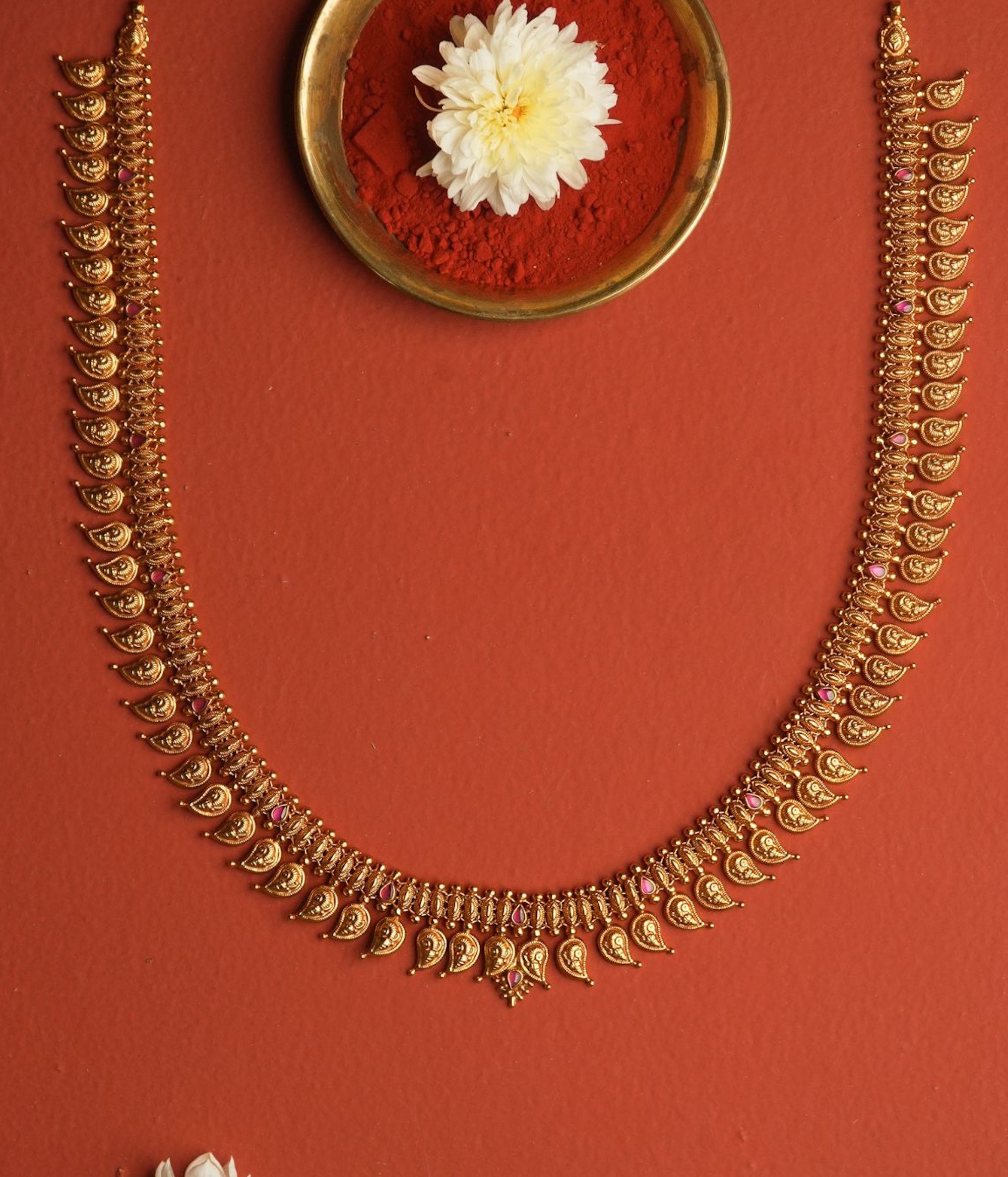 Gold necklace with decorative elements on a red background