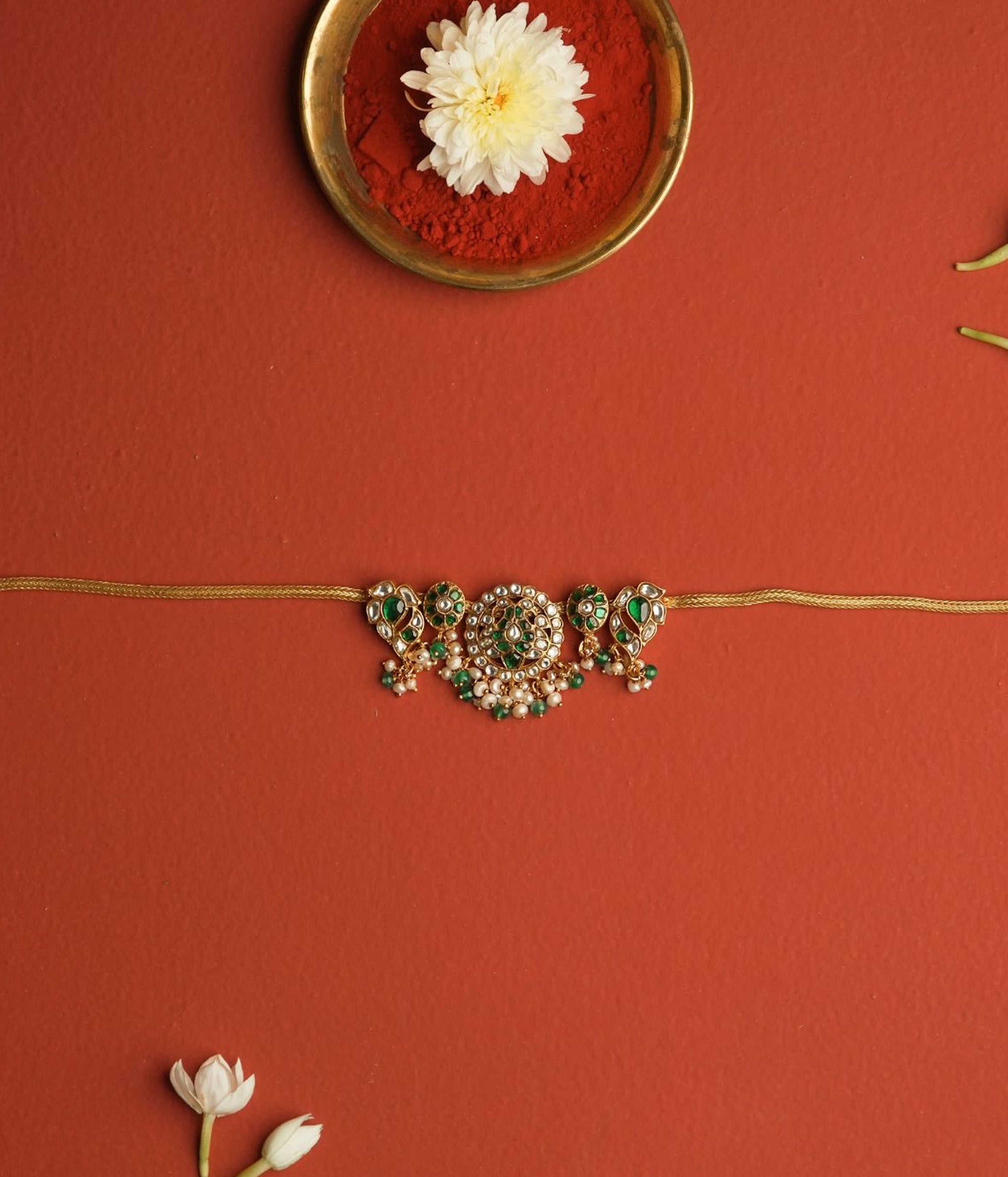 Decorative attigai with green and gold details on a red background